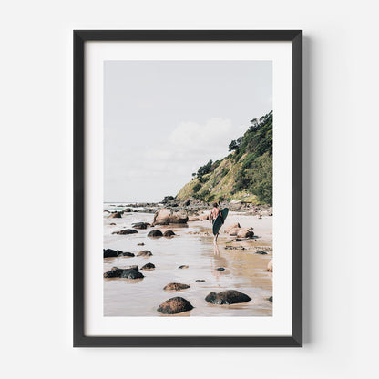 Serene Beach Adventure: Coastal Surfer Walking Along Rocky Shoreline