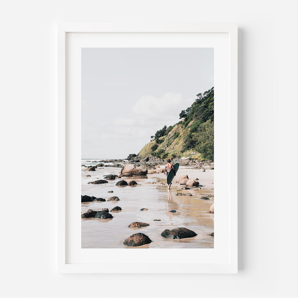 Serene Beach Adventure: Coastal Surfer Walking Along Rocky Shoreline