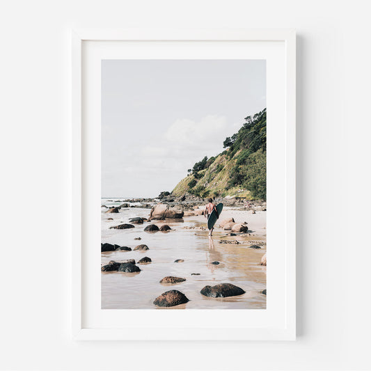 Serene Beach Adventure: Coastal Surfer Walking Along Rocky Shoreline