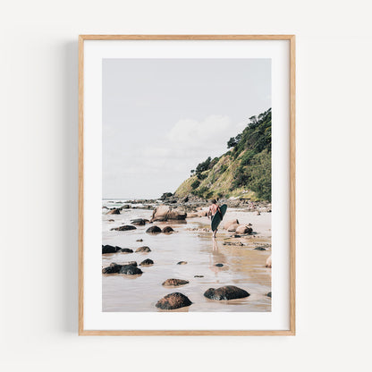 Serene Beach Adventure: Coastal Surfer Walking Along Rocky Shoreline